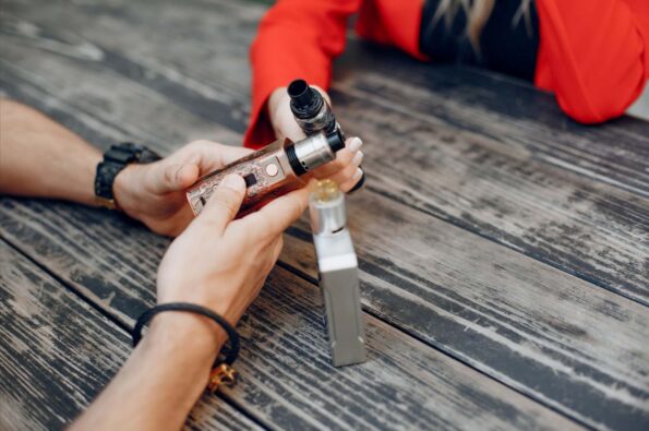 a young couple, each holding a vape.