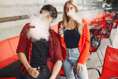 Stylish young couple with vape