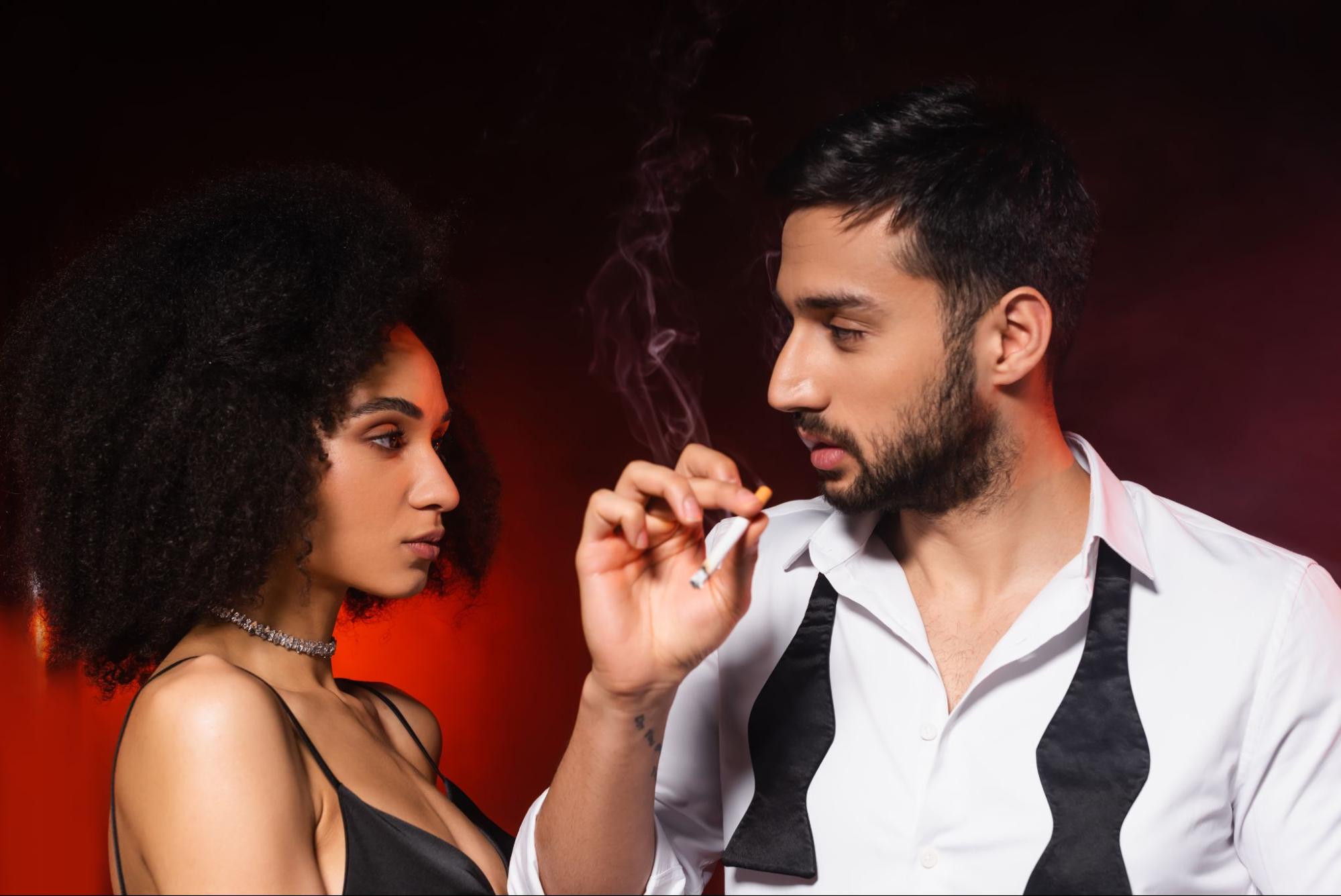Man smoking a cigarette near a woman.
