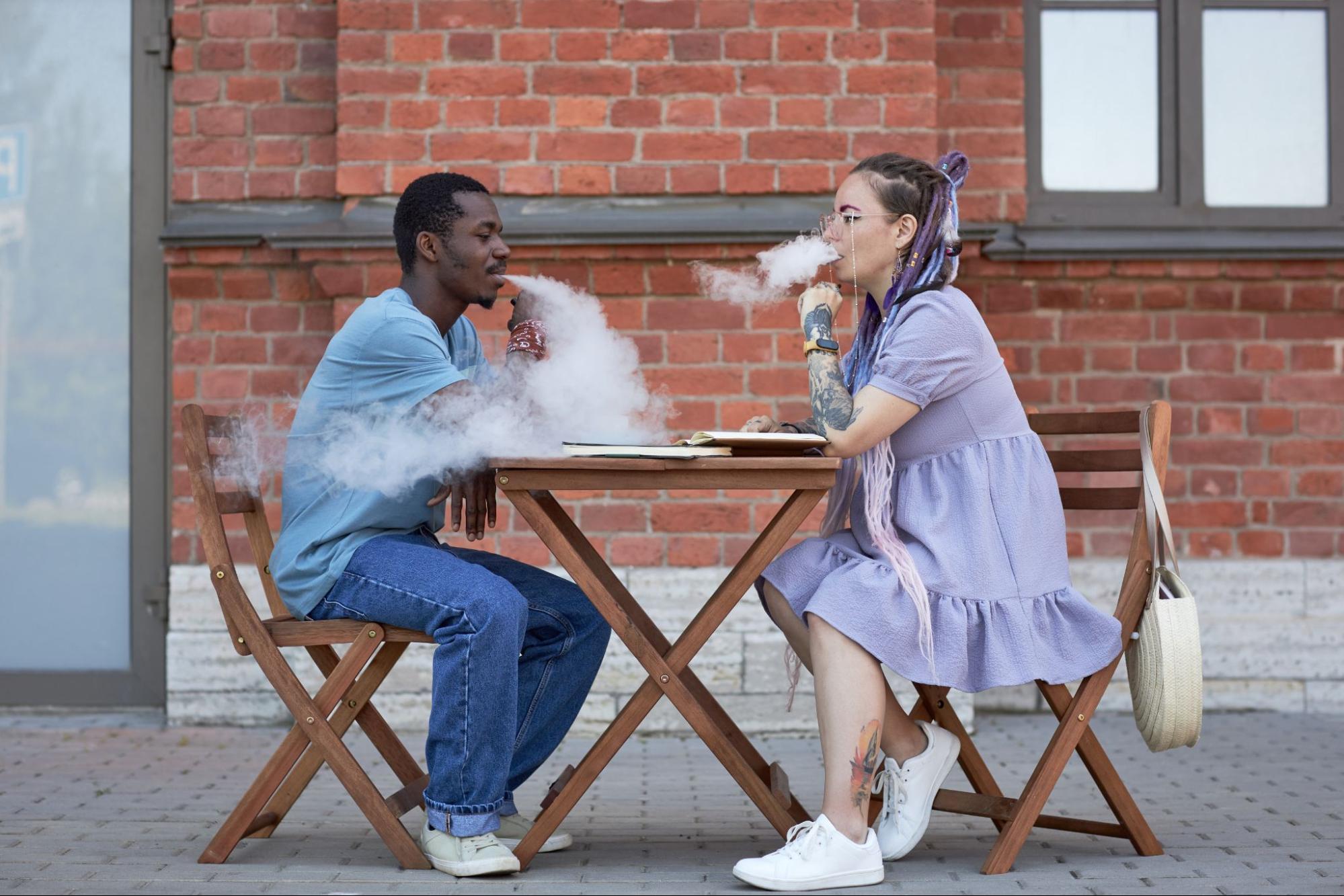 Side view of two young intercultural colleagues smoking at a meeting