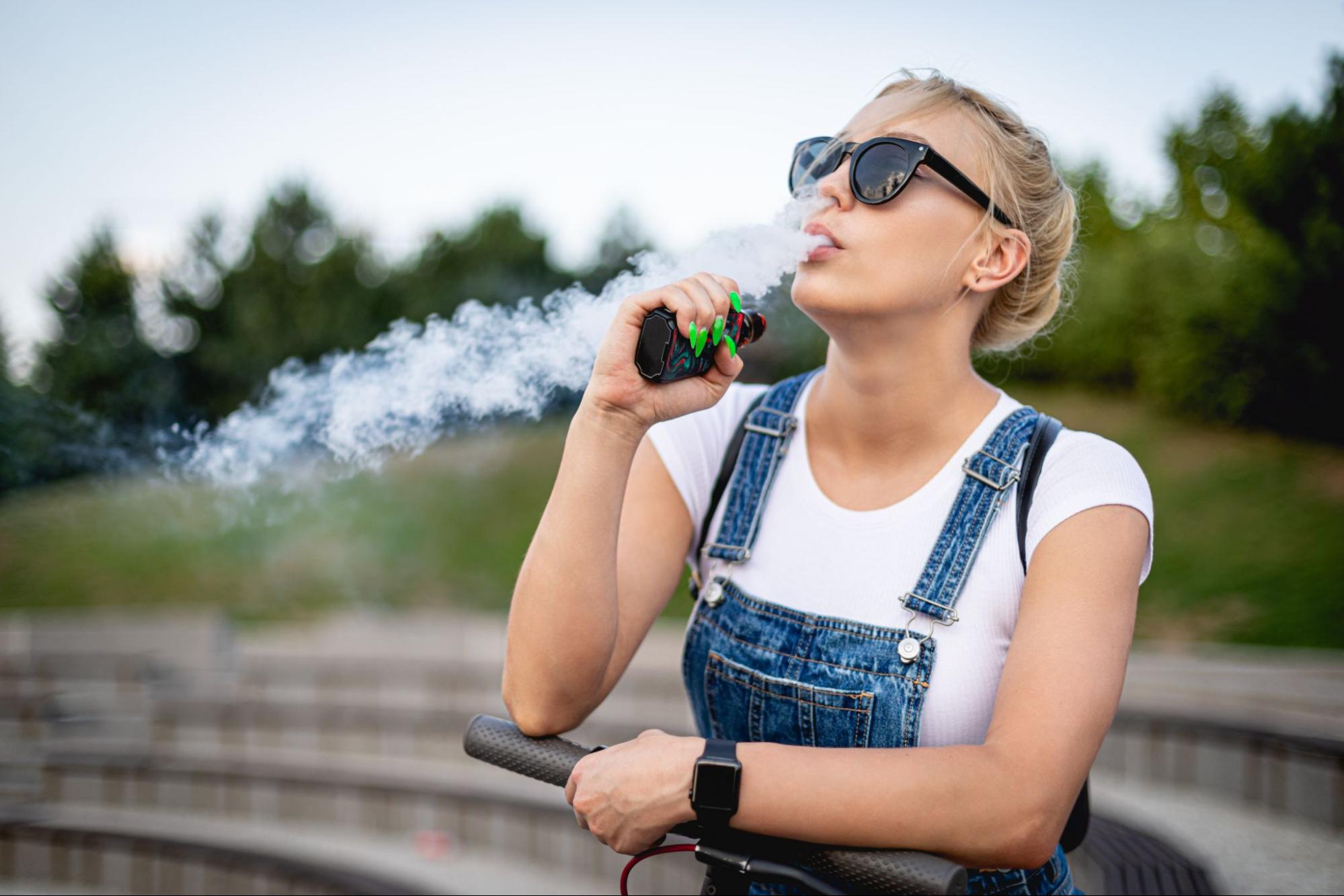 Woman using a vaping device outdoors.