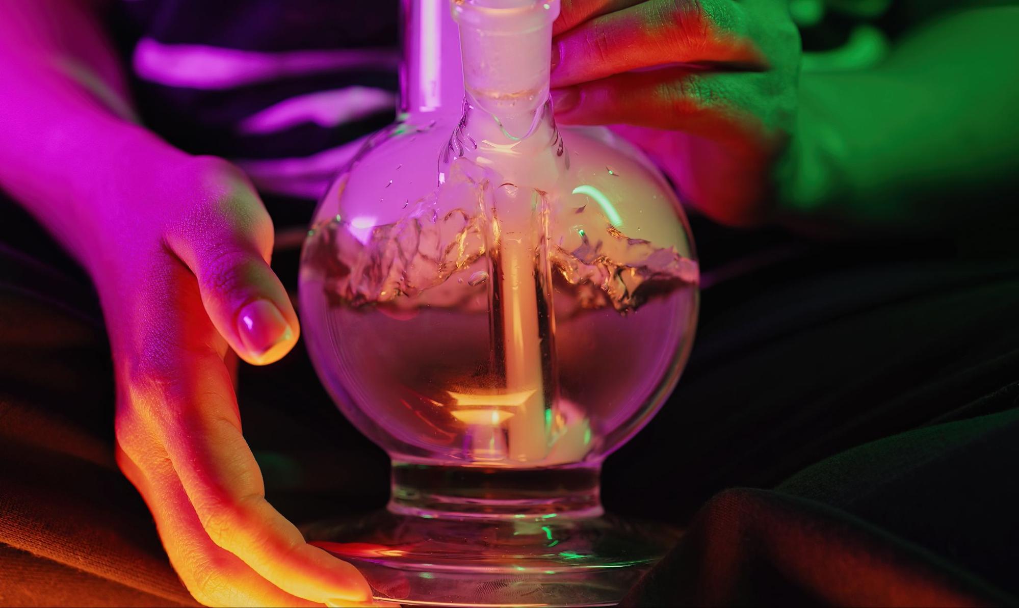 Woman with painted nails using a bong.