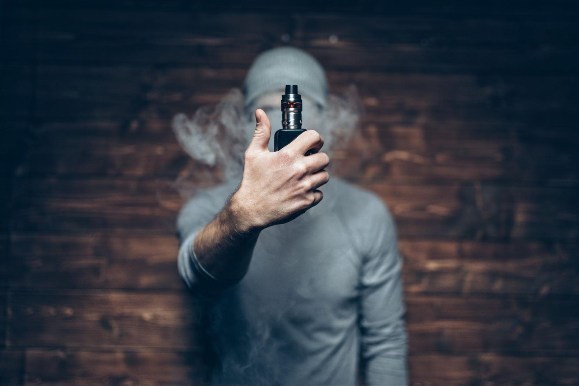 A man enjoys vaping flavored e-liquid from an electronic cigarette.