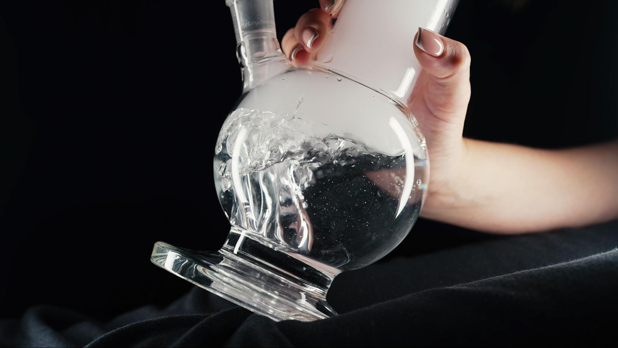 Woman holding a glass bong in her hand.