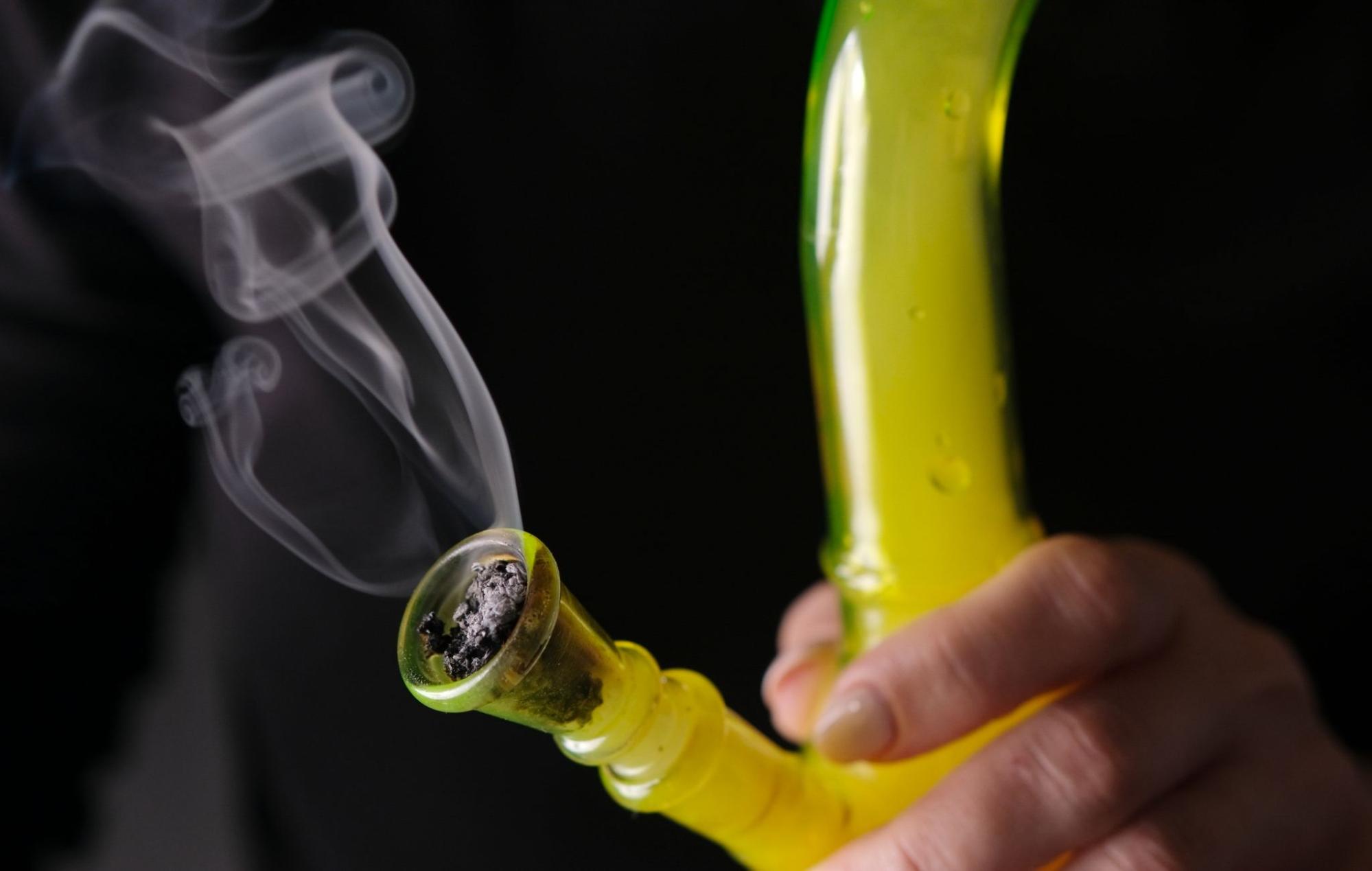 Person using a bong and smoking weed.
