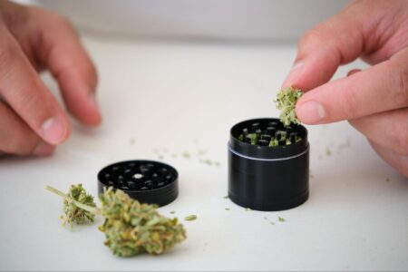 Person putting marijuana in a weed grinder.