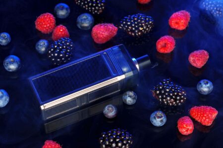 Sleek black and silver vape box mod displayed on a dark background, complemented by assorted berries.