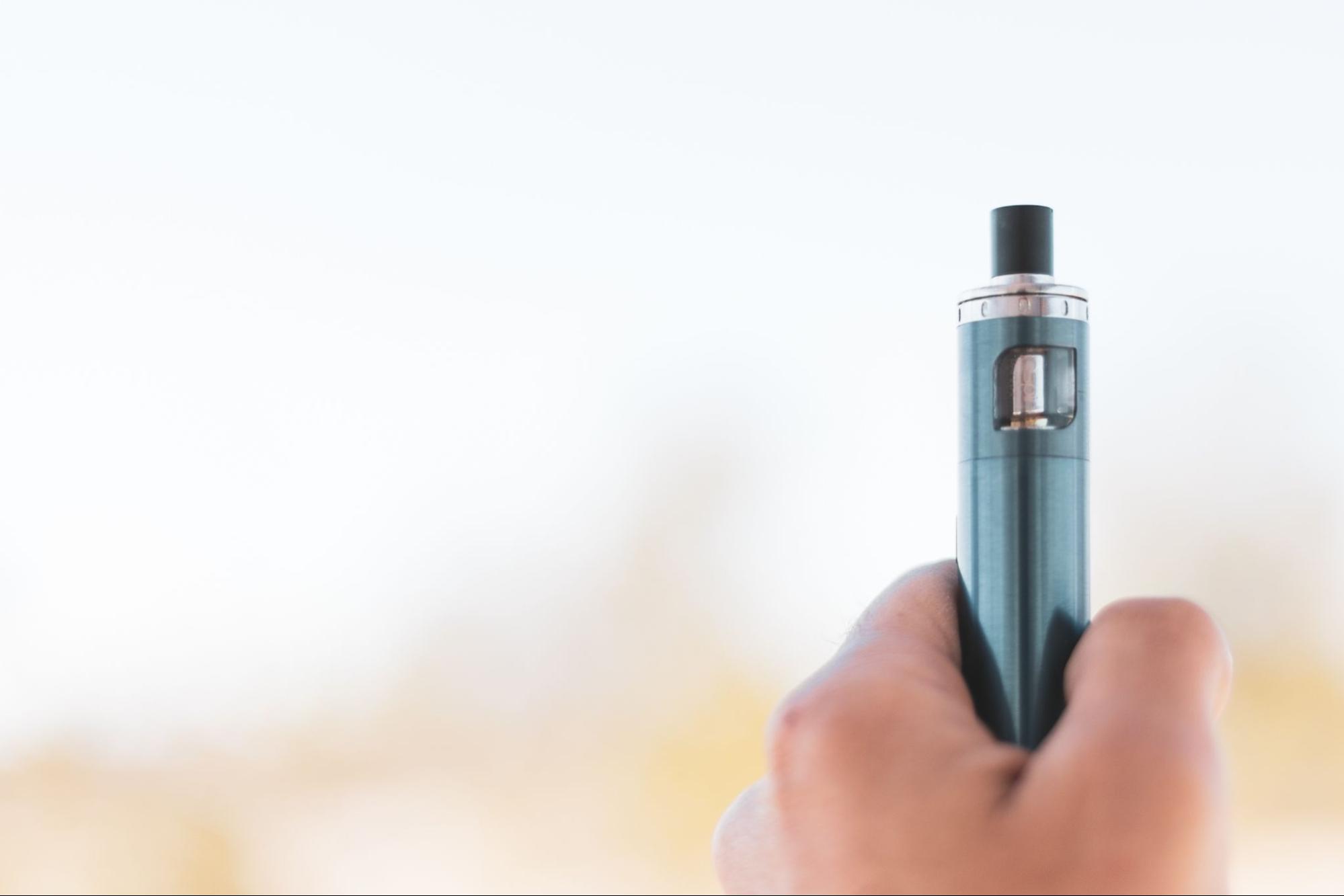 A hand holding a vape device.