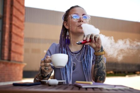 A picture of a woman enjoying her coffee while vaping.