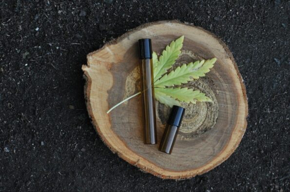 A cropped view of a blue vaporizer pen next to a cartridge and ground marijuana on top of a wooden surface.