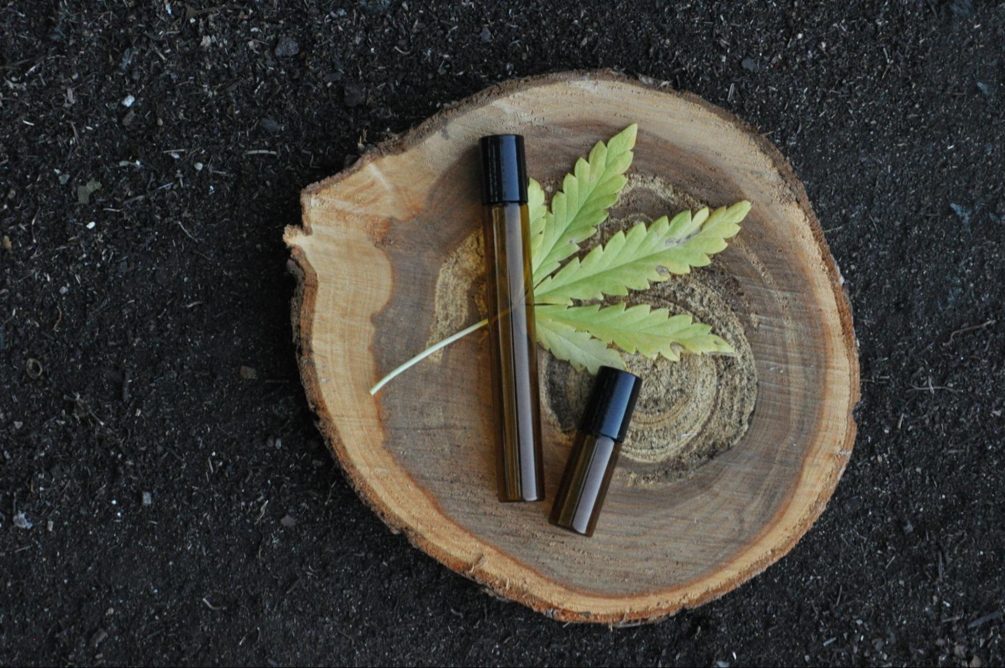 A cropped view of a blue vaporizer pen next to a cartridge and ground marijuana on top of a wooden surface.