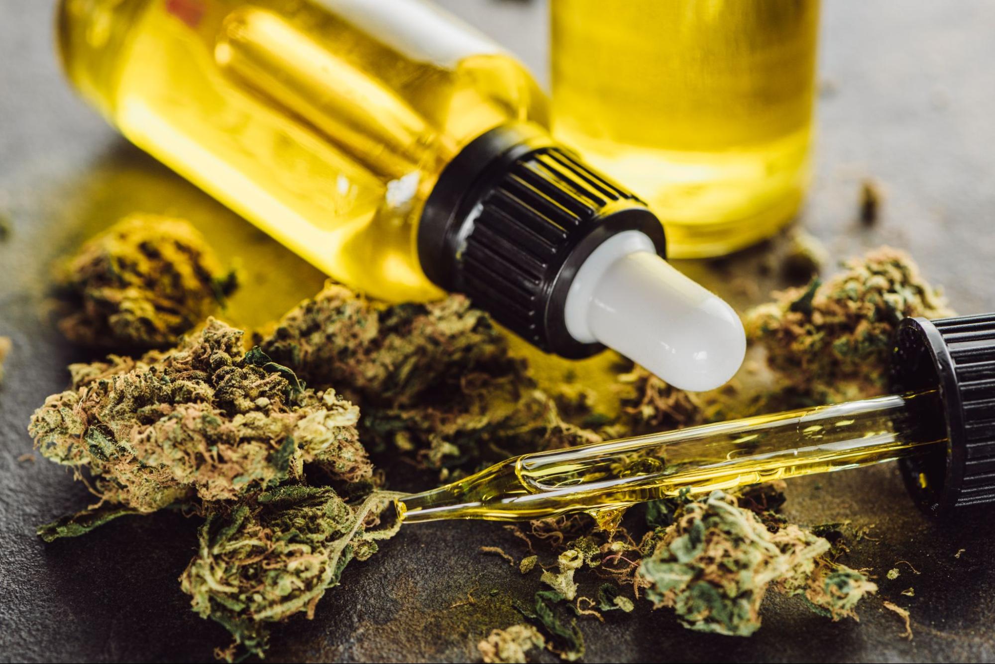 Two bottles of cannabis oil on top of some marijuana buds.