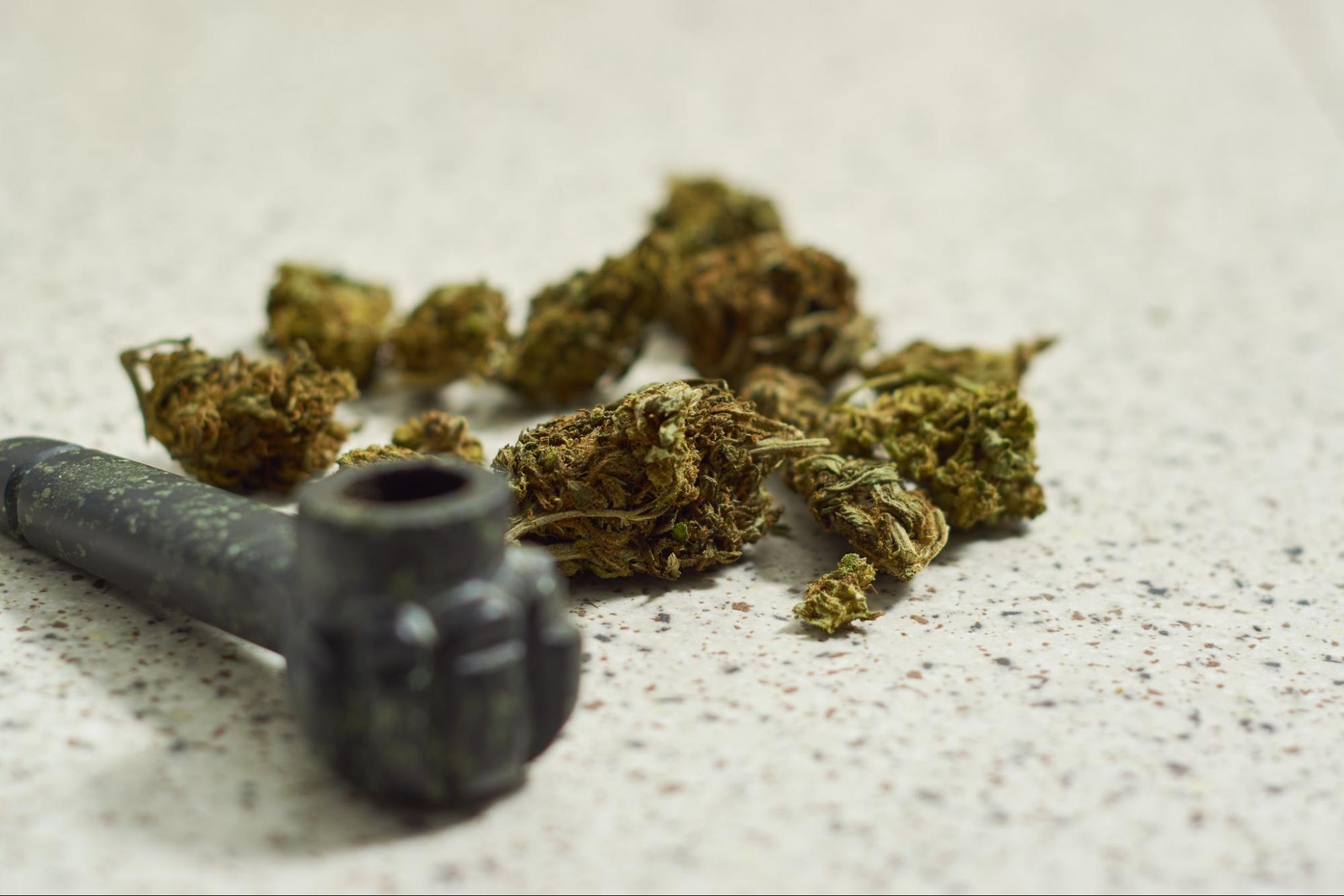 Marijuana buds next to a pipe. 
