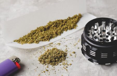 Weed cannabis grinder and cigarette lighter on grey background