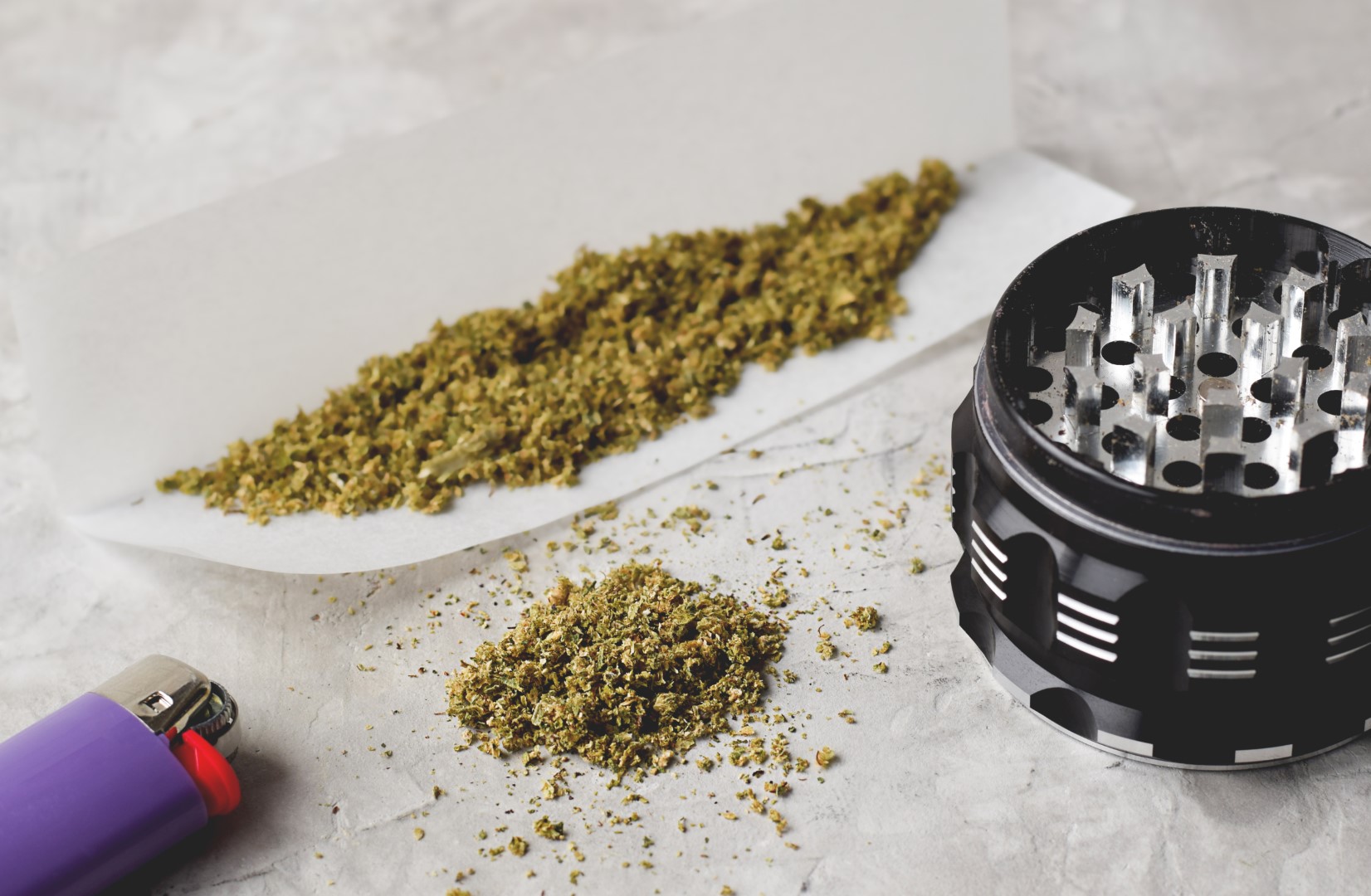 Weed cannabis grinder and cigarette lighter on grey background