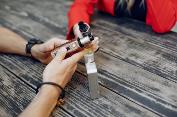 Two people holding vape devices.