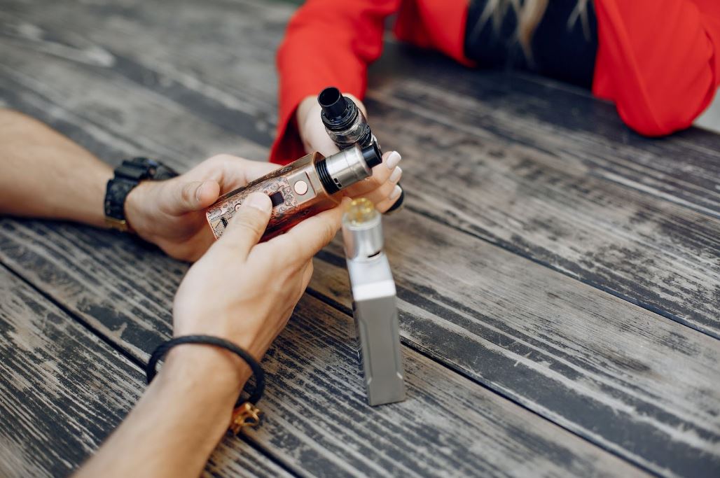 Two people holding vape devices.