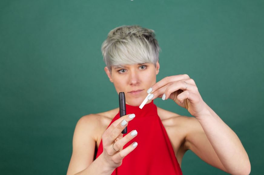 Woman holding a vape and a cigarette.