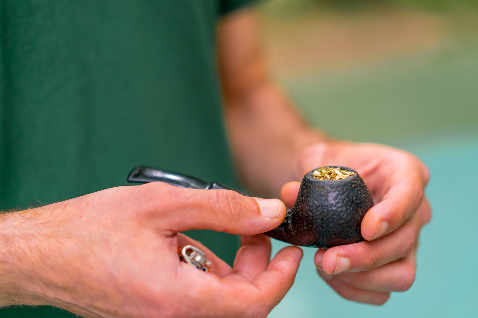 Cropped view of a man’s hand holding a pipe with cannabis in the bowl.