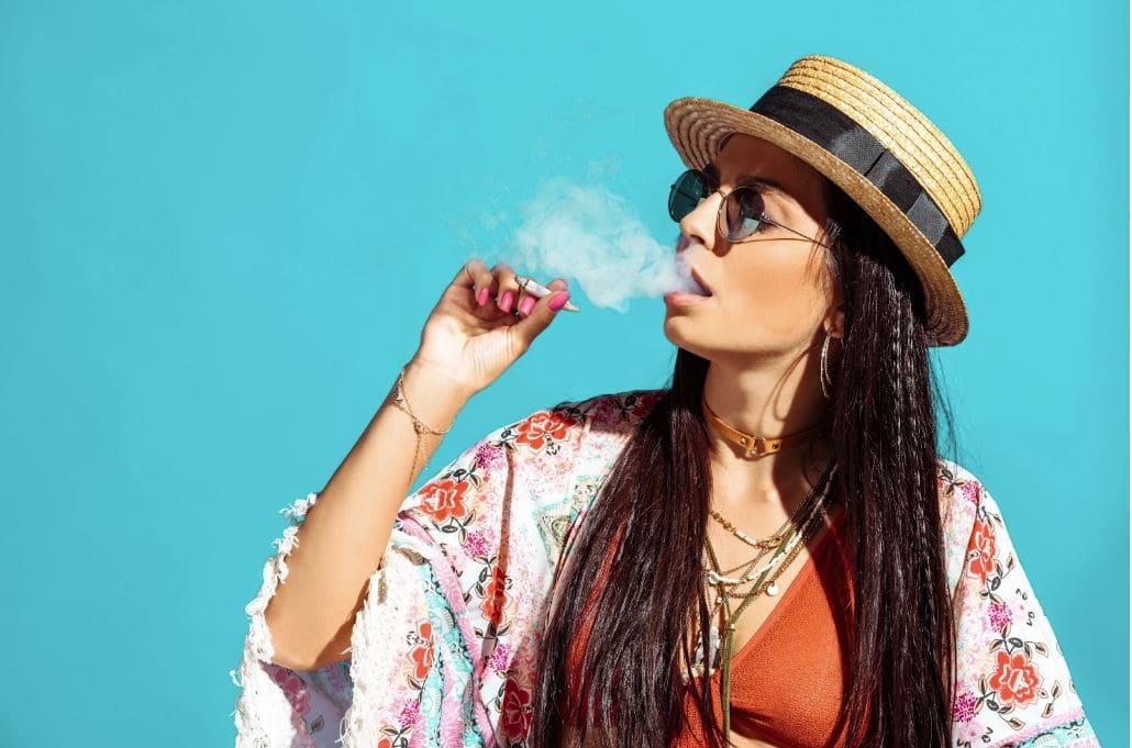 Woman in a hat and sunglasses smoking cannabis.