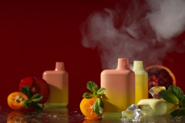 Disposable vapes surrounded by ice and fruits.