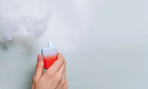 Woman with painted nails holding a disposable vape.