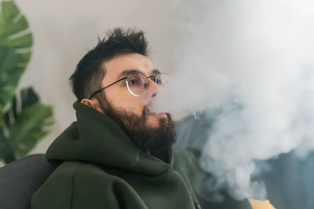 a close up of a man blowing smoke out after hitting a bong a close up of a man blowing smoke out after hitting a bong