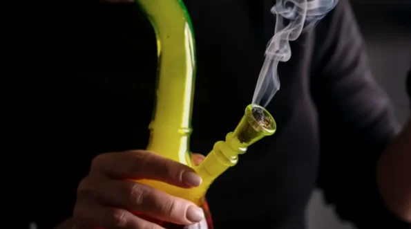 person using a bong with smoke coming out